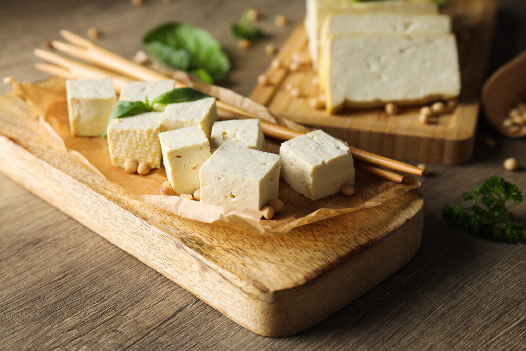 Fotografia przedstawia miseczkę z pokrojonym tofu w towarzystwie chrupiących warzyw i orzechów. Kolorowa potrawa zachęca do eksperymentowania z roślinnymi źródłami białka. Zdjęcie podkreśla, jak tofu może wzbogacić catering dietetyczny pod względem smaku i wartości odżywczych.